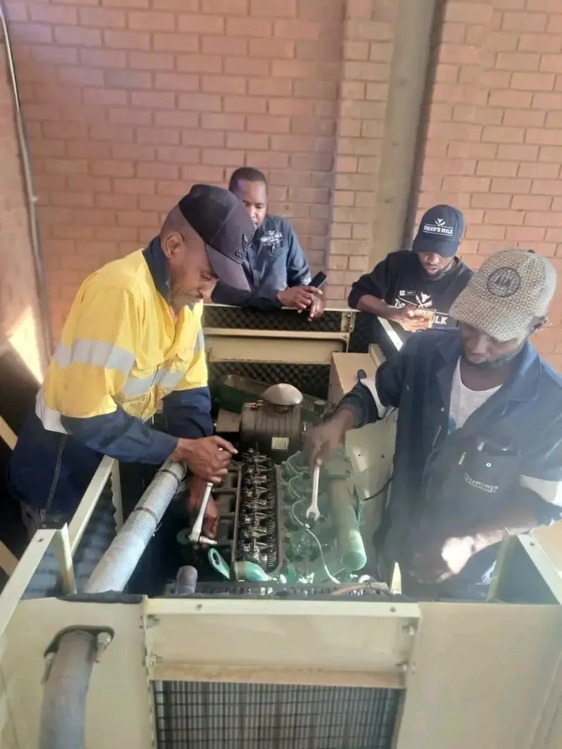 Technicians working on an open diesel generator engine