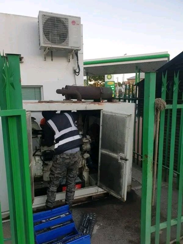 Technician working inside an open generator canopy on site
